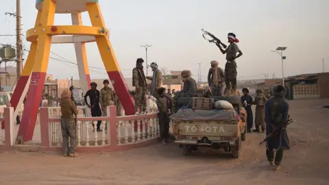 Combattants en camouflage sur une route poussiéreuse au Mali