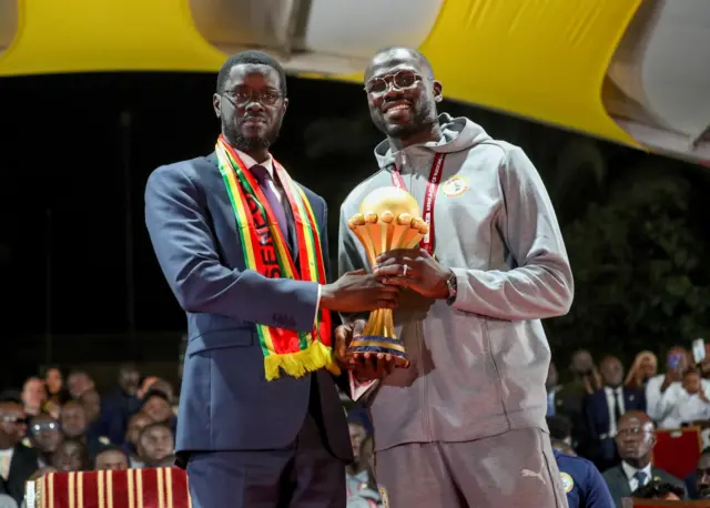 Le président sénégalais Bassirou Diomaye Faye et le capitaine de l'équipe nationale, Khalidou Koulibaly, tenant le trophée de la Coupe d'Afrique des Nations