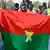 Des partisans de l'AES brandissent un drapeau du Burkina Faso fait maison